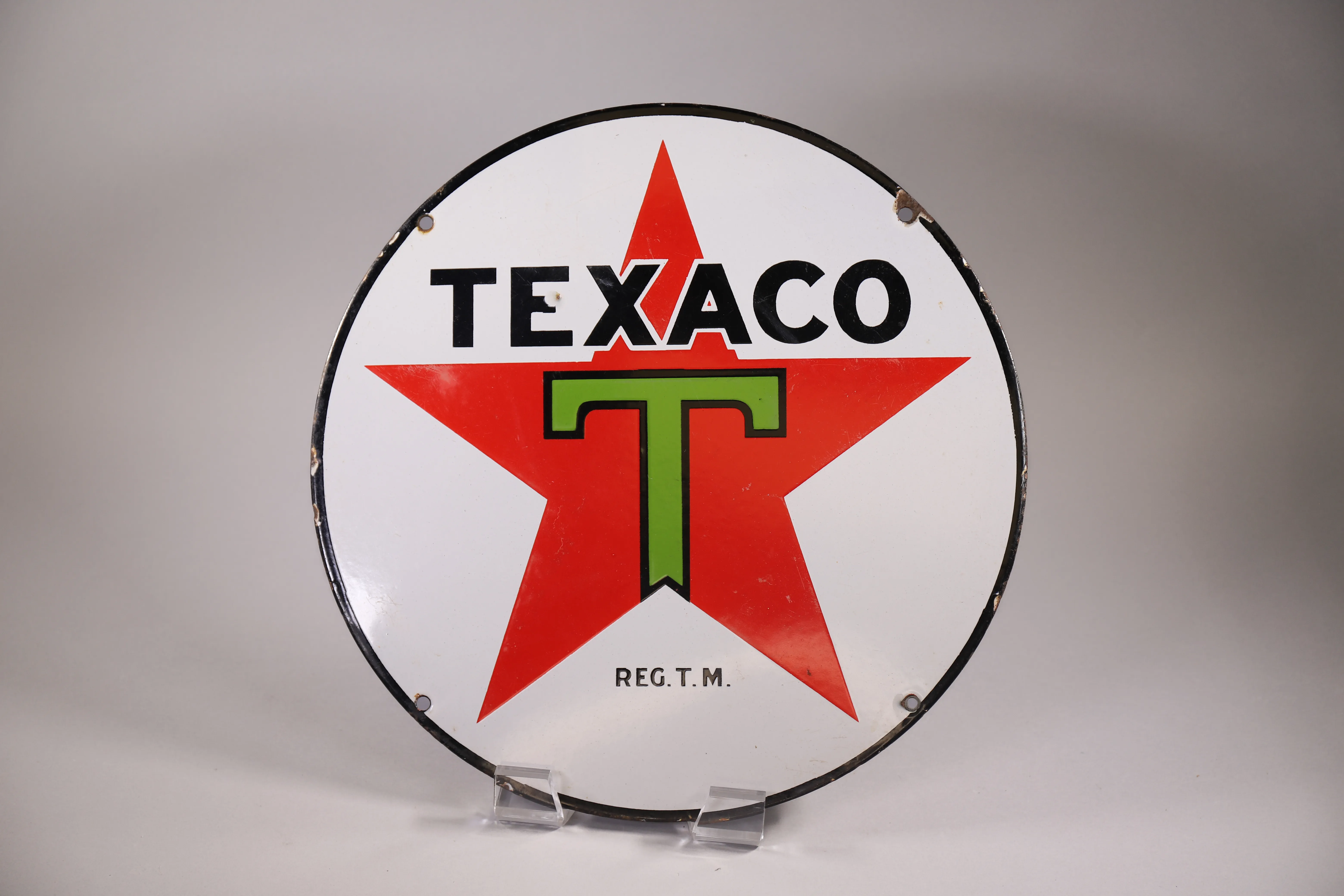 Round Texaco star sign photographed as an automotive and garage-adjacent estate sale collectible.